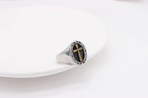Macro detail of oval signet ring featuring golden cross with Swim and Sink text