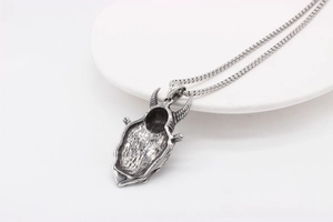 Detailed view of punk style silver metal bull skull pendant on a sleek ball chain necklace