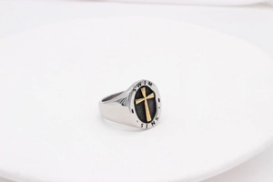 Macro shot of silver signet ring with golden cross and SWIM SINK engraved text