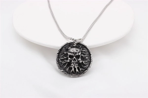 Detailaufnahme des Vintage-Punk-Totenkopfanhängers mit oxidiertem Finish auf Sockel