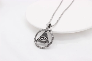 Macro detail of silver stainless steel pendant with All-Seeing Eye and Ouroboros snake