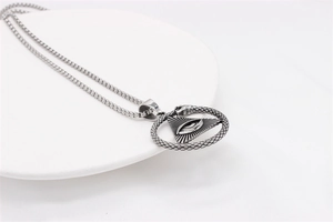 Close-up of vintage Eye of Providence pendant with Ouroboros symbol on steel chain