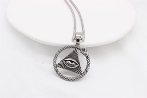 Macro shot of vintage stainless steel All-Seeing Eye and Ouroboros snake pendant details