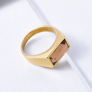 Minimalist gold titanium steel ring with rectangular amber gemstone on white background