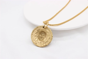Vue détaillée du pendentif doré avec portrait en relief et finition martelée