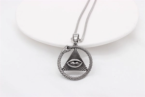 Macro shot of silver vintage All-Seeing Eye and Ouroboros pendant with aged texture