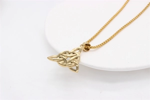 Détail d'un pendentif nœud celtique Triquetra doré sur une fine chaîne à billes en acier