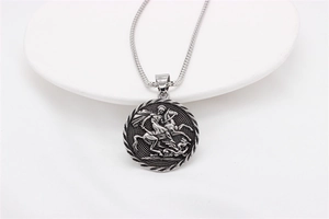 Detail of vintage silver St. George pendant with relief on a white display tray