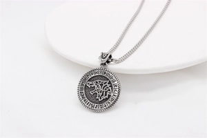 Detail of Viking wolf head pendant with Nordic runes on matte silver steel jewelry