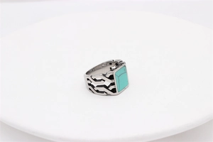 Macro view of vintage steel ring featuring a green rectangular stone and hollow geometric detail