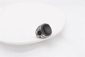 Close-up of a vintage steel ring featuring a square black stone and geometric engravings