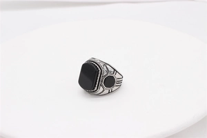Detail of vintage men's stainless steel ring with rectangular black gemstones and filigree