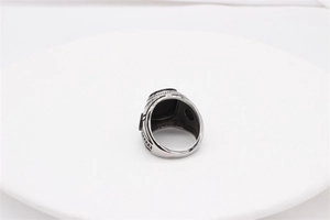 Macro detail of men's vintage steel ring with square black gemstone and carved texture