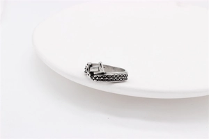 Macro detail of retro silver dagger sword ring with knurled texture on ceramic plate