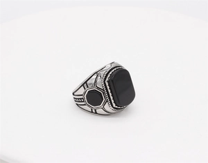 Macro shot of retro steel ring featuring a rectangular black stone and geometric carvings