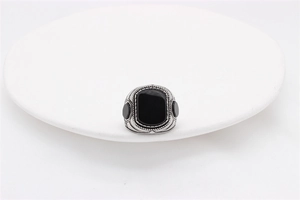 Macro detail of men's vintage ring featuring a rectangular black gem and engraved silver band