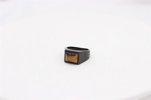 Detail of a matte black ring band featuring a square tiger eye stone inlay on a white pedestal