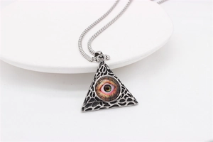 Macro detail of silver-toned pyramid pendant featuring the All-Seeing Eye and mesh texture
