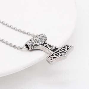 Vintage Thor's hammer Mjölnir pendant necklace in silver stainless steel on white surface