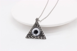 Detailed shot of retro gothic pyramid eye pendant on a white tray with metal ball chain