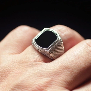 Nahaufnahme eines Herrenrings in Silber mit schwarzem Edelstein und Perlenstruktur