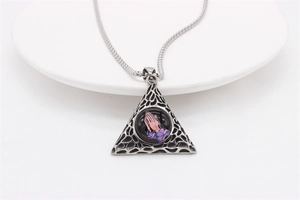 Detailed view of silver triangle pendant featuring praying hands art on a white tray