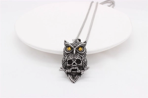 Detail of vintage dark owl pendant necklace with yellow gem eyes and skull motif