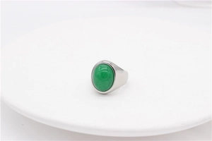 Détail macro d'une bague ovale argentée avec une grande pierre verte sur plat blanc