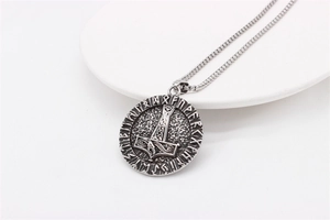 Macro detail of vintage steel pendant featuring Mjölnir emblem and runic letters