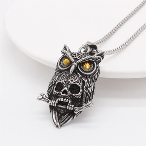 Vintage owl skull pendant necklace in antique silver with amber eyes on white ceramic