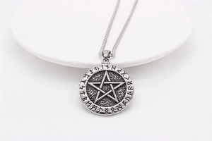 Macro detail of vintage Nordic Viking star pendant with engraved ancient runes on steel