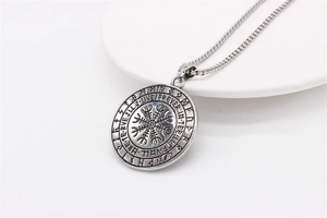 Detail of vintage Viking compass Vegvisir pendant with Runic alphabet on stainless steel