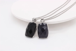 Gros plan sur les pendentifs rectangulaires en agate noire et pierre de sable bleue