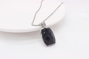 Vue détaillée du collier pendentif rectangulaire en pierre de sable bleu sur céramique
