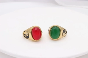 Detail of vintage gold steel rings featuring red and green gems with Yin Yang symbols