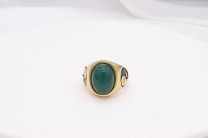 Detailed macro view of vintage gold ring featuring green gemstone and tai chi swirls
