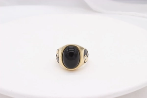 Detailed macro view of gold-tone ring featuring a black stone and yin yang side motif