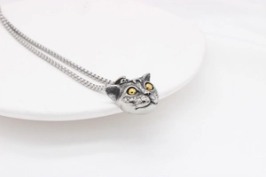 Macro detail of retro style cat pendant with golden eyes on a steel box chain