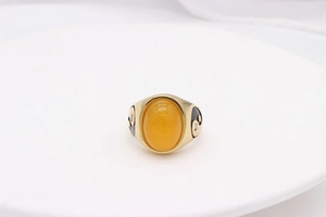 Macro shot of gold vintage ring with large oval yellow stone and black enamel details