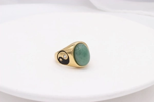 Detailed side view of vintage gold ring with green oval stone and yin yang emblem