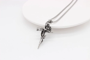 Détail du pendentif croix avec rose en acier inoxydable argenté sur assiette