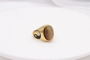 Detailed close-up of golden vintage signet ring featuring Yin Yang symbols and tiger eye stone