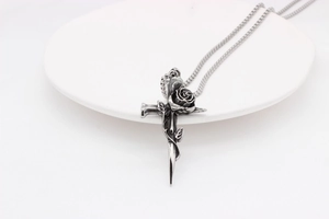 Détail d'une rose gothique s'enroulant autour d'un pendentif croix en acier vintage