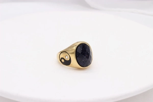 Macro detail of gold vintage ring with oval blue sandstone and Yin Yang side symbol