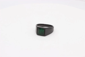 Détail d'une bague en titane noir mat ornée d'une pierre précieuse verte de taille carrée