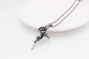 Vue macro d'un collier avec pendentif croix épée et rose gothique en acier inoxydable