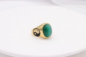 Macro view of gold-plated ring with a large green oval cat-eye stone and yin-yang symbols