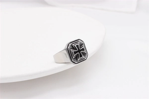 Detail of vintage steel ring with black cross relief on a white ceramic plate