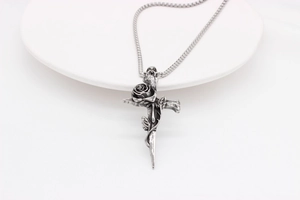 Détail d'un collier gothique argenté avec un pendentif croix et rose au style vintage