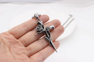 Gros plan d'un pendentif croix vintage avec détails de rose en acier titane oxydé